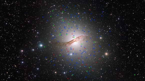 This huge elliptical galaxy NGC 5128 (also known as Centaurus A) is the closest such galaxy to the Earth, at a distance of about 12 million light-years. Observations with ESO’s Very Large Telescope in Chile have discovered a new class of “dark” globular star clusters around this galaxy. These are marked in red. Normal globulars are marked in blue and globulars showing similar properties to dwarf galaxies are in green. The dark globulars appear very similar to other globulars around this galaxy but contain much more mass. Image credit: ESO/Digitized Sky Survey. Acknowledgement: Davide de Martin.
